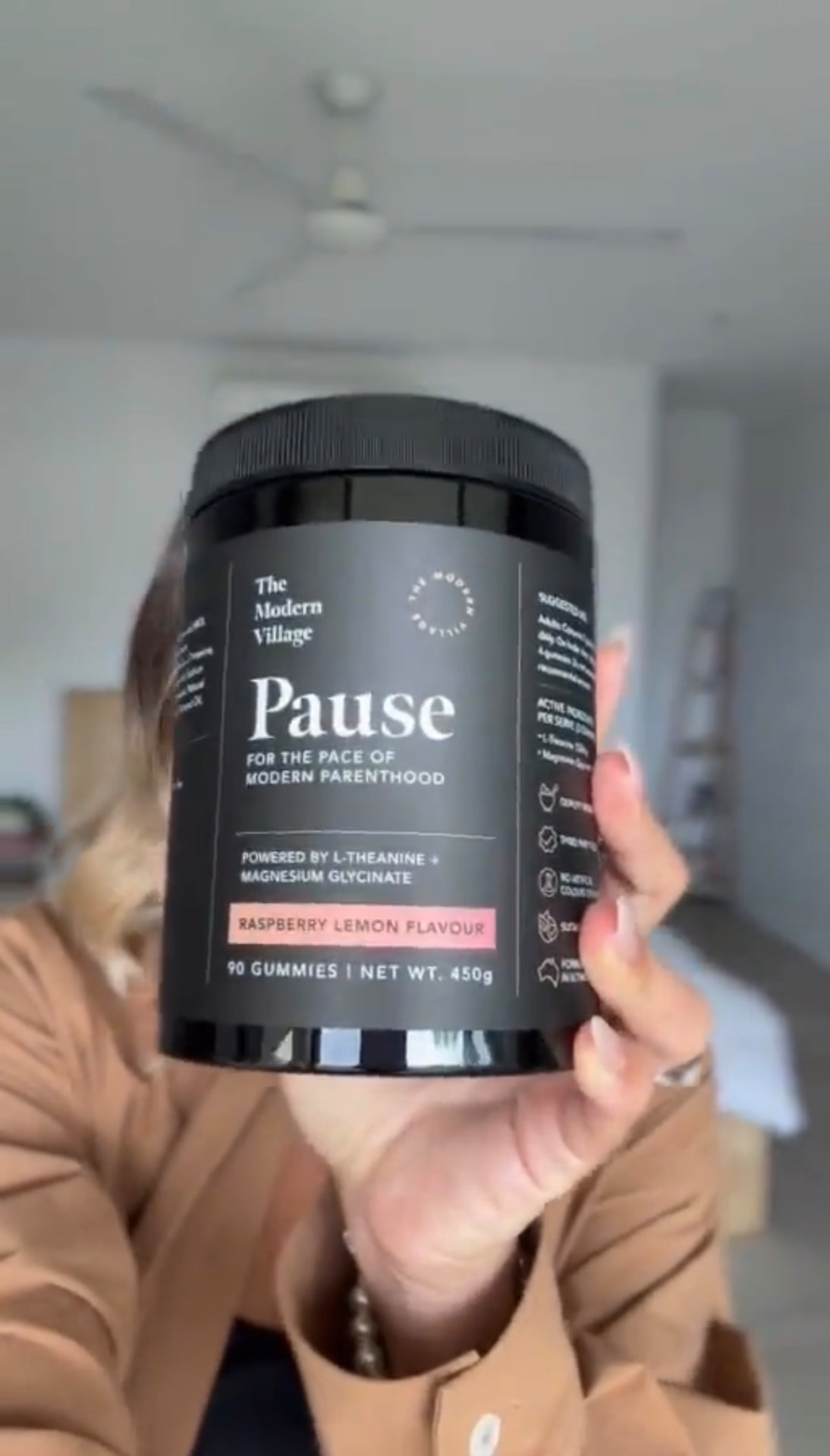 A mum in her kitchen holding a jar of Pause gummies.